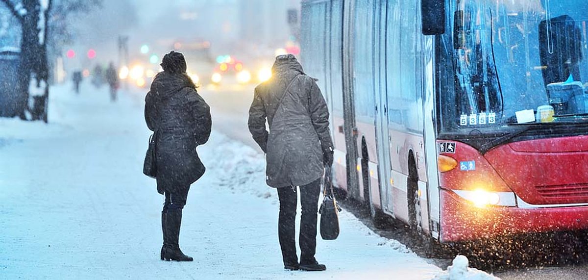Zwei Personen stehen vor einem Bus während es schneit