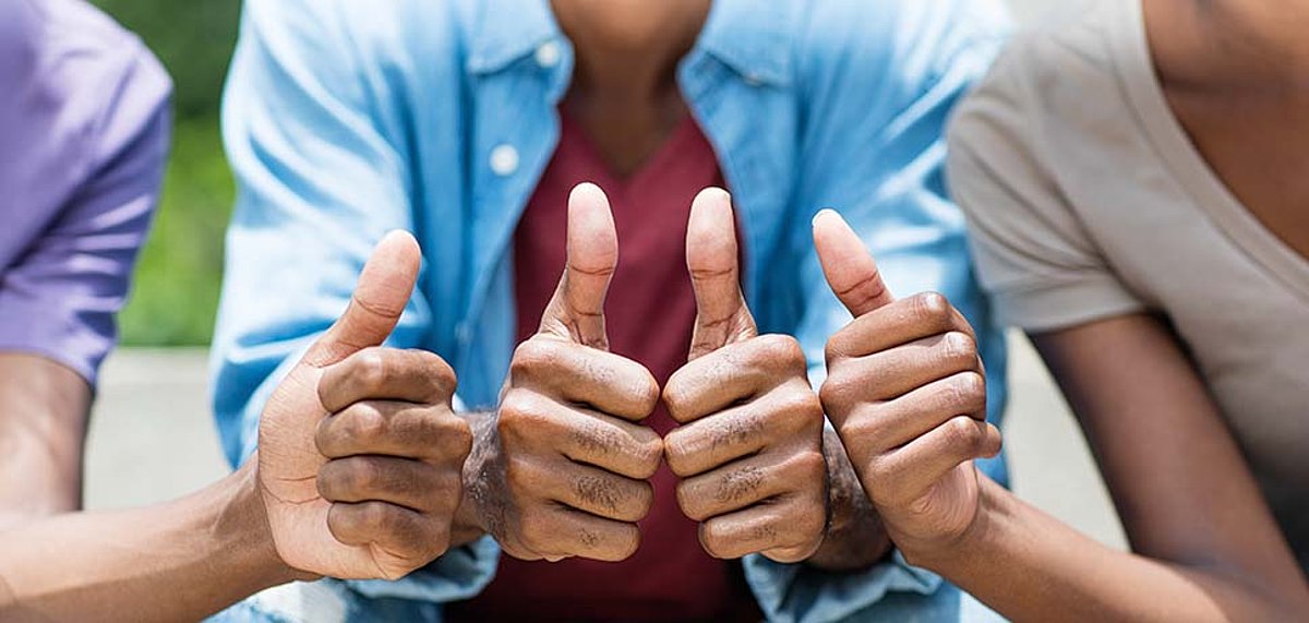 Drei Personen halten Ihre Hände mit Daumen hoch zusammen