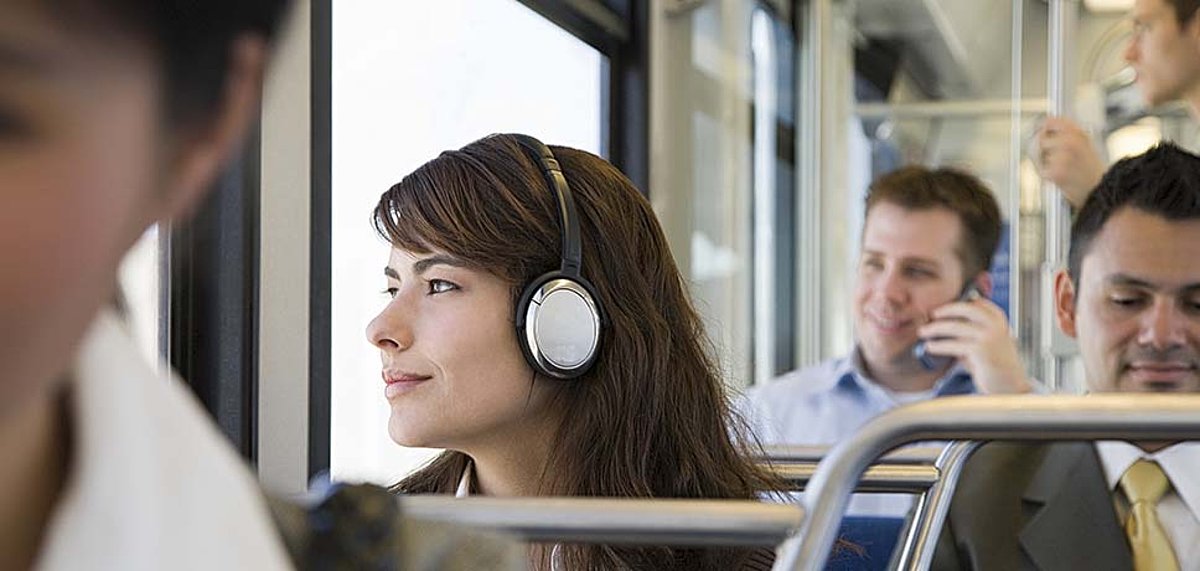 Eine junge Frau mit Kopfhörern schaut aus dem Bus