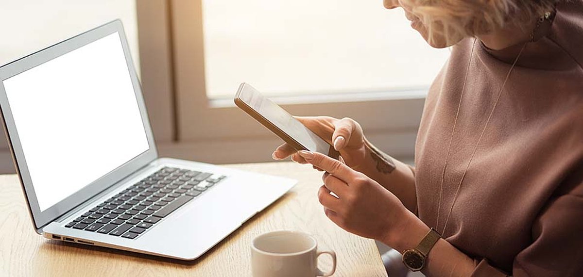 Frau arbeitet mit Laptop und Handy