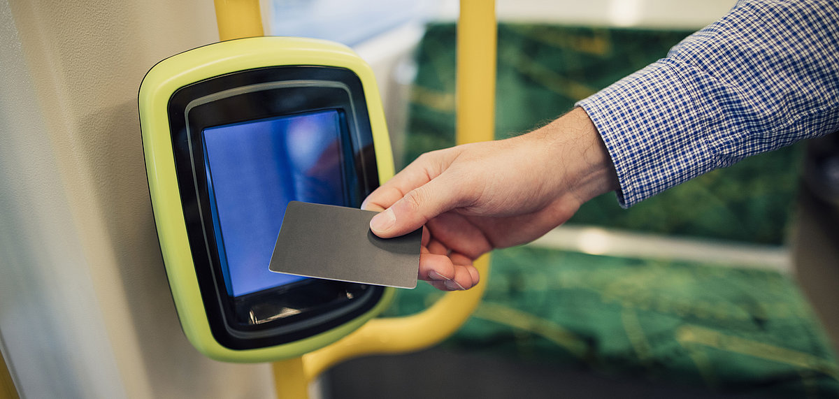 Mann hält Karte an e-Ticket-Terminal